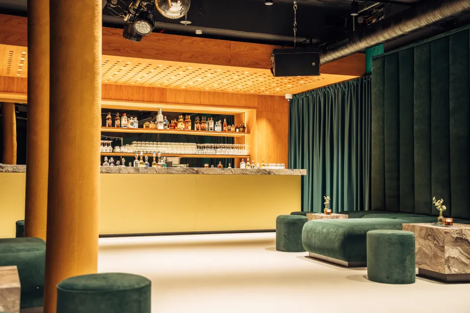 OSCHO: Bar mit gelber Säule, Marmortheke und grünen Samtvorhängen