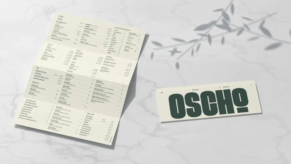 OSCHO: aufgefaltete Getränkekarte und die Kartenhülle mit großer Wortmarke auf Marmor